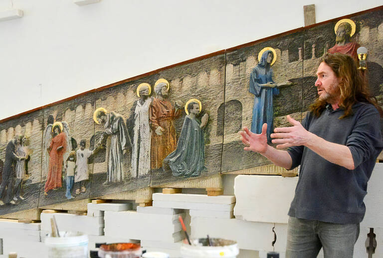 Thomas Lucker vor dem von ihm geschaffenen Steinrelief in der St. Marien-Kirche.