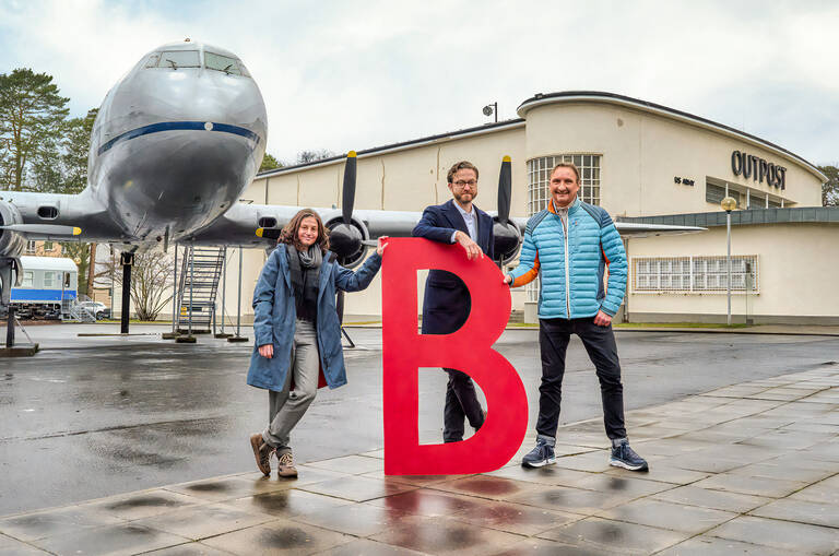 A wie AlliiertenMuseum: Veit Lehmann vom AlliiertenMuseum mit Michael Pawlik (rechts) und Jule Steinert (links) von der Wirtschaftsförderung Steglitz-Zehlendorf vorm Luftbrücken-Flugzeug. Foto: Sebastian Wunderlich / Gröschel Branding