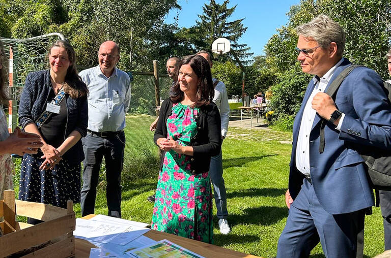 Senatorin Günther-Wünsch (m.) und Bezirksbürgermeister Oltmann (r.) am Bienenstand in der Gartenarbeitsschule. Foto: BATS