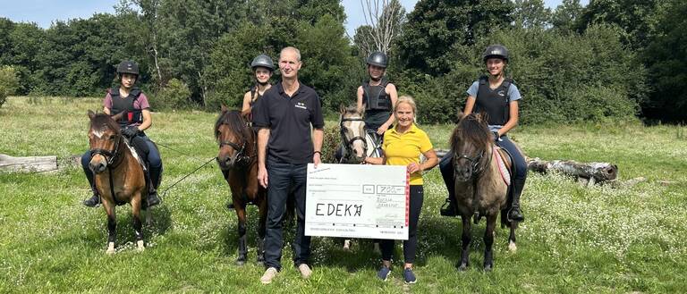 Glinda Spreen, 1. Vorsitzende des KJRFV, freut sich über die Spende. Den Scheck übergab Patrick Erler auf dem Reitgelände des Vereins am Königsweg.  Foto: KJRFV Zehlendorf e.V.